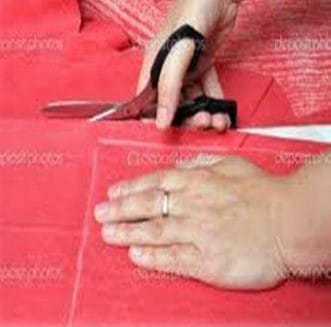 A tailor cutting and stitching embroidered Chikankari fabric into elegant garments like kurtas, sarees, and dupattas.